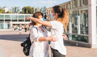 Yeni normal. Anne ve kızı yeni normallik içinde birbirlerini kucaklıyorlar. Anne ve kızı birbirlerine maskeyle sarılıyorlar.