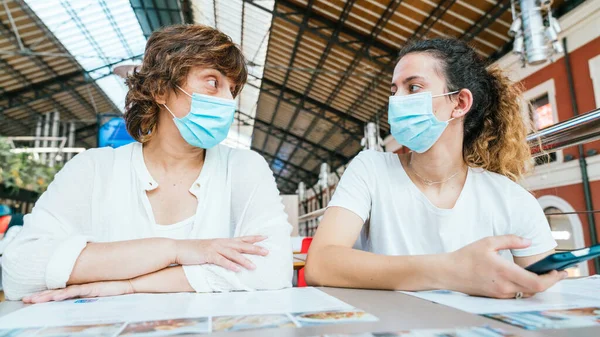 Anne ve kızı maskeli bir restoranda restoranın menüsünü okuyorlar. Yeni normallik. Maskeli bir restoranda yemek sipariş etmek. Maskeli yeni bir hayat. Yeni normallikte boş zaman