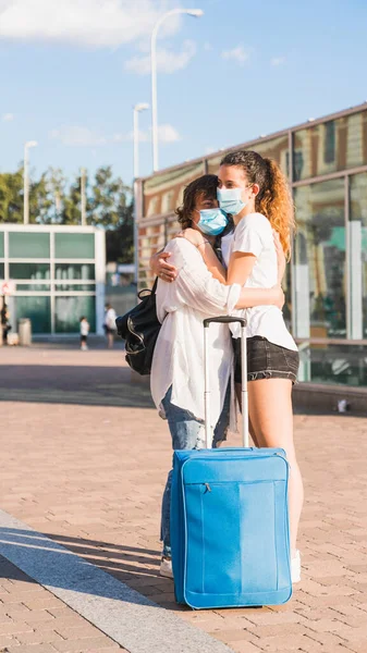 Yeni normal. Anne ve kızı yeni normallik içinde birbirlerini kucaklıyorlar. Anne ve kızı birbirlerine maskeyle sarılıyorlar. Anne, kızını kucaklayarak karşılıyor. Havaalanı. Tren istasyonu..