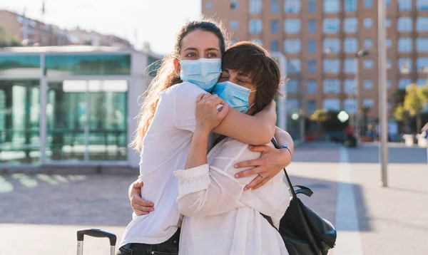 Yeni normal. Anne ve kızı yeni normallik içinde birbirlerini kucaklıyorlar. Anne ve kızı birbirlerine maskeyle sarılıyorlar. Sevgi. Aile