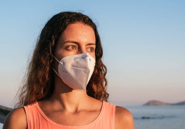 Sahilde koronavirüs maskesi takıyordu. Halka açık yerlerde tıbbi maske takmak. Coronavirus karantinası. Covid-19 salgınında seyahat ve tatil.