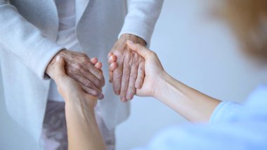 Yaşlı bir kadının elini nazikçe tutan bir hemşirenin yanına yaklaşın. Rahatlık, empati ve sağlık hizmetlerinde bir bağlantı hissi sunar.