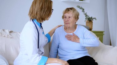 Kadın doktor, evde göğüs ağrısı ya da rahatsızlığı olan yaşlı bir kadına bakım ve destek veriyor. Sağlık hizmetlerine şefkatli ve ilgili bir yaklaşım sergiliyor.