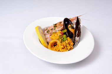 Beyaz arka planda deniz mahsullü paella.