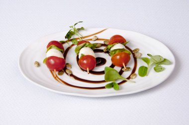 Beyaz arka planda bir tabak domates ve peynir salatası.