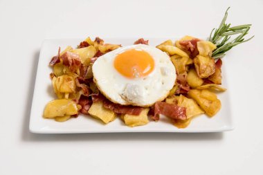 Beyaz arka planda yumurta ve jambonlu bir tabak patates.
