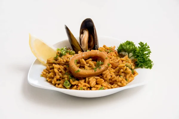 Beyaz arka planda deniz mahsullü paella.