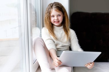 Kız internete giriyor. Liseli kız çevrimiçi çalışıyor. Evde eğitim. Bilgisayarın önünde yorgun bir çocuk. Mesafe ve çevrimiçi eğitim ve çocuklar için uzaktan öğrenme. Karantinada evde eğitim.
