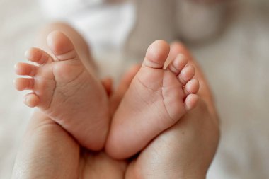 Bebeğin küçük ayakları, annenin ellerindeydi. Aile içinde sevgi. Aile değeri. Bir annenin yeni doğmuş bir çocuğa olan sevgisi. Mutlu çocukluk kavramı.