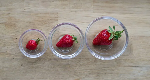 Transparente Glasschale mit Erdbeeren isoliert auf Holzhintergrund — Stockfoto