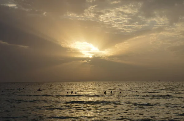 Beau coucher de soleil au dessus de la mer ou de l'océan. Couleurs vibrantes et douces, lumière magique. Petits nuages sur le ciel, reflet du soleil dans l'eau et du sable sur la plage — Photo