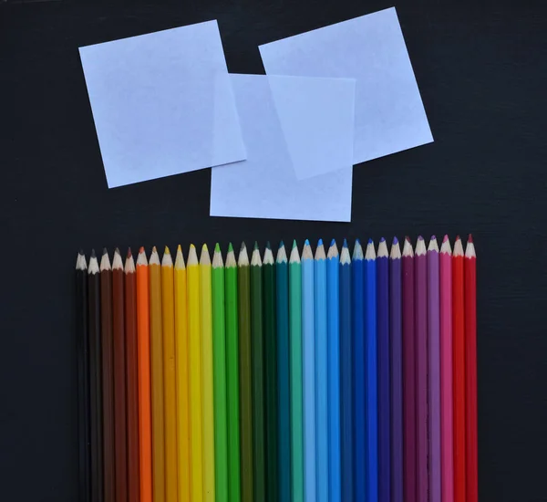 Цветные карандаши с белыми квадратными листами на черном фоне. Собрание рисунков для произведений искусства. Место для заметок — стоковое фото
