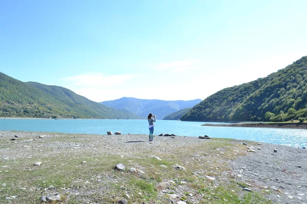 Kadın alarak sakin mavi göl ve resmi dağlar, Georgia