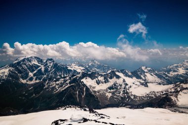Mavi gökyüzüne karla kaplı görkemli dağlar. Kristal temiz hava ve kabarık bulutlar. Kafkasya 'nın nefes kesici manzarası
