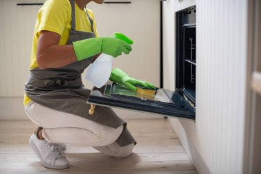 Profesyonel mutfak temizliği. Hizmetçi fırını yıkar. Lastik eldivenli bir kız toprağı siliyor. Temizlik ve hijyen.