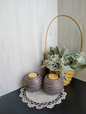 Hasır bir sepetin içinde iki tane safran mumuyla yünlü Stachys bitkisi.