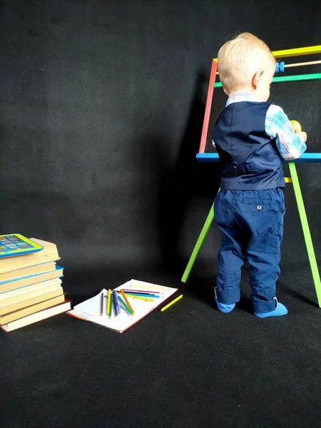 Niño pequeño con un traje azul de pie junto a la pizarra —  Fotos de Stock