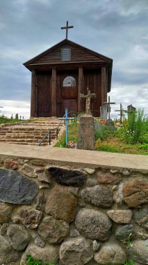 Taş bir duvarın arkasındaki mezarlıkla çevrili küçük ahşap bir kilise.