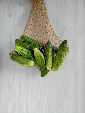 Bahçeden gelen salatalıklar hafif bir ahşap arka planda bir ip torbasında