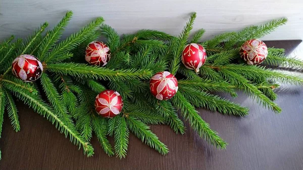 붉은 크리스마스 장식이 달린 가문비나무 가지를 다듬어 어두운 나무 배경에 놓는다 — 스톡 사진