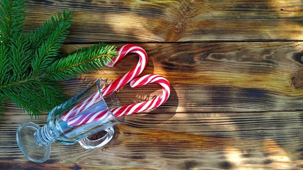 冷杉枝干和圣诞节棒棒糖，装在木制背景的杯子里 — 图库照片
