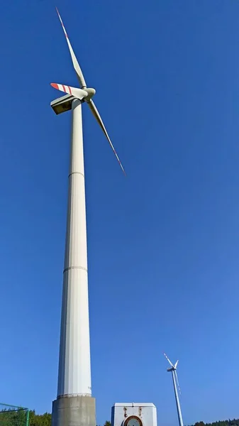 Twee witte windgeneratoren tegen de blauwe lucht — Stockfoto