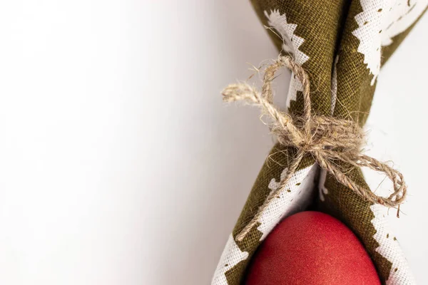 Yeşil peçetedeki kırmızı Paskalya yumurtası doğal iplikle bağlanmış.