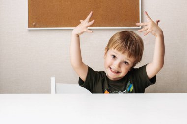 Yazı masasındaki komik çocuk suratını buruşturuyor.