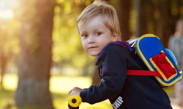 Çocuk motosikletle ve sırt çantasıyla, günbatımı ışığı