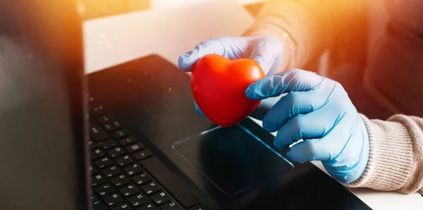 Ev bilgisayarında çalışan bir adam korunmak için tek kullanımlık eldiven giyiyor. Coronavirüs salgını. Karantinaya alınmış bir iş adamı. Evde çalış. Evde kal..