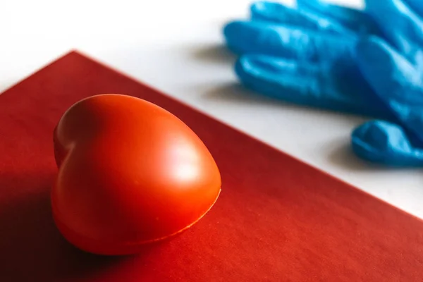 Beyaz arka planda lateks koruyucu lastik eldiven ve yanında da kırmızı bir kalp. Sağlık sigortası konsepti. Coronavirus koruması covid-2019. Tıbbi konsept. Tıp eğitimi.