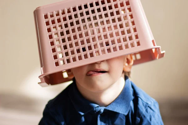 Kafasında çamaşır sepeti olan bir bebek.