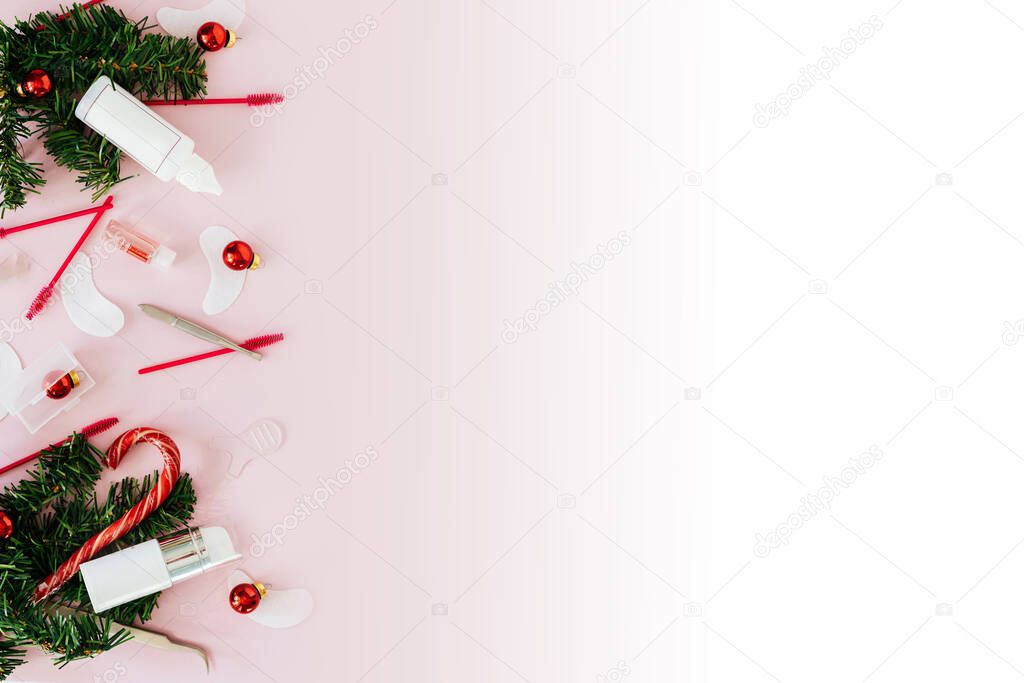 Beauty salon and lash artist tools and treatment products on left side lay out creating a frame on a pink white background with a Christmas theme. Christmas tree toys with tools for treatment. Copy