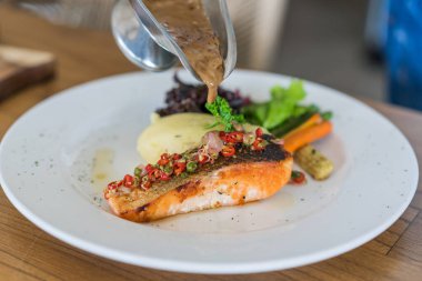 Baharatlı ızgara somon bifteği, patates püresi ve marul. 