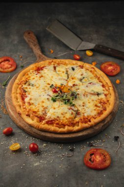 Taze pizza ve ahşap masada yemek malzemeleri.