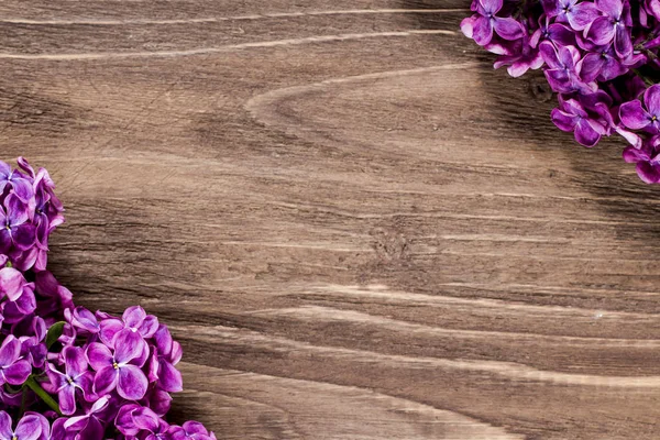 Soldaki aşağı ve sağ yukarı köşe kahverengi ahşap yüzeyde leylak çiçeği.