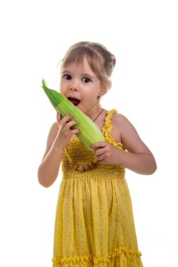 Mısır kulak ile parlak sarı elbiseli küçük kız. Studio fotoğraf, parlak beyaz arka plan.