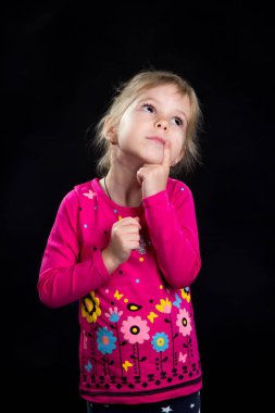 Duygu kavramı: rüya gibi sevimli küçük kız. Siyah arka plan, studio fotoğraf.