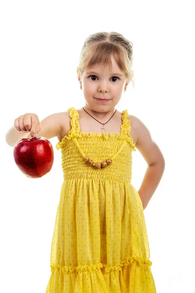 Klein meisje in een helder gele jurk met een appel in haar handen. Studio foto, lichte geïsoleerde achtergrond. — Stockfoto