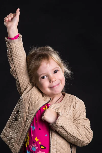 Conceito de emoção: menina feliz com um braço levantado. Fundo preto, foto do estúdio . — Fotografia de Stock