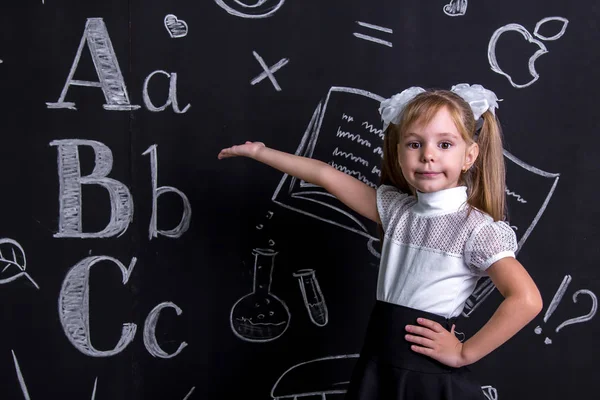 Poważne uczennica stojący przed chalkboard jako tło wskazujący ręka do tablicy. Obraz pejzaż — Zdjęcie stockowe