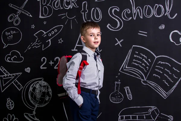 Szczęśliwy uczniak stojąc przed chalkboard jako tło z plecakiem na plecach. Obraz pejzaż — Zdjęcie stockowe