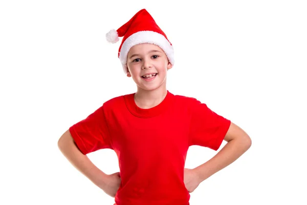 Ładny uśmiechnięty chłopiec, santa kapelusz na głowie, z ramionami na pasie. Koncepcja: Boże Narodzenie lub nowy rok wakacje — Zdjęcie stockowe
