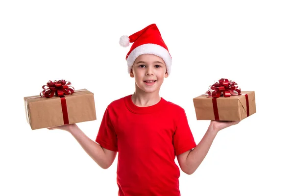 Guapo niño feliz, sombrero de santa en la cabeza, con dos cajas de regalo en las manos, mirando directamente a la cámara. Concepto: Navidad o Feliz Año Nuevo —  Fotos de Stock