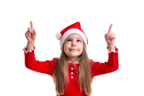 Meisje van de kerst met wijzende vingers omhoog, dragen een kerstmuts geïsoleerd op een witte achtergrond — Stockfoto