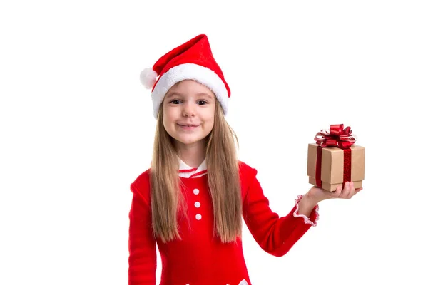 Gelukkig Kerstmis meisje bedrijf van een gift in de linkerhand, dragen een kerstmuts geïsoleerd op een witte achtergrond — Stockfoto