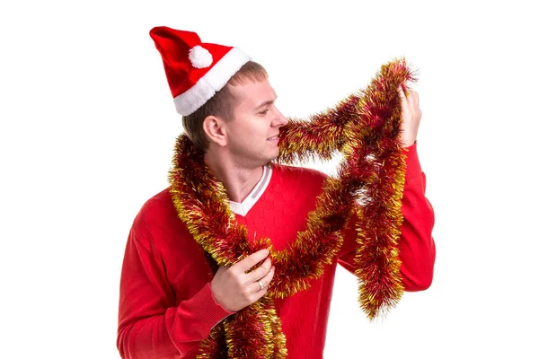 Lustiger erwachsener Kerl mit Weihnachtsmütze und Lametta um den Hals, der das Lametta betrachtet — Stockfoto
