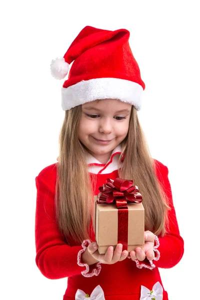 Feliz Navidad niña sosteniendo y mirando el regalo en las manos, usando un sombrero de santa aislado sobre un fondo blanco —  Fotos de Stock