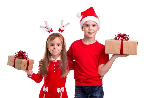 Niño feliz con sombrero de santa en la cabeza y una chica con cuernos de ciervo, sosteniendo las cajas de regalo en sus manos. Concepto: Navidad o Feliz Año Nuevo —  Fotos de Stock