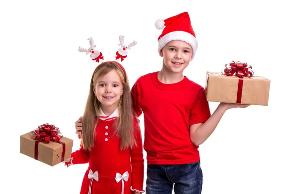 Χαρούμενος ο αδελφός με santa καπέλο στο κεφάλι του και μια αδελφή με κέρατα ελαφιών, κρατώντας το δώρο κουτιά στα χέρια τους. Έννοια: Χριστούγεννα ή ευτυχισμένο το νέο έτος διακοπές — Φωτογραφία Αρχείου